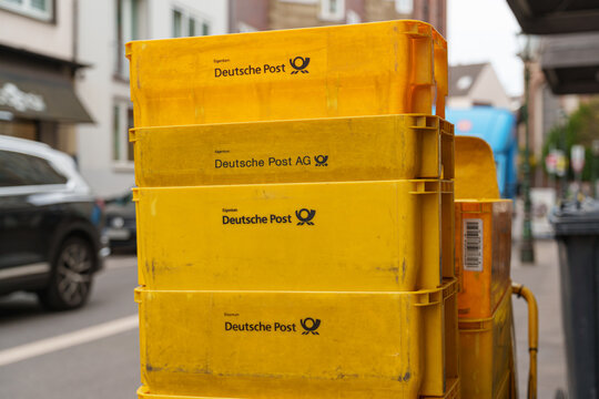 Dusseldorf, Germany - October 31 2025: Deutsche Post delivery cart waits beside quiet storefronts on a calm city street in Altstadt central district