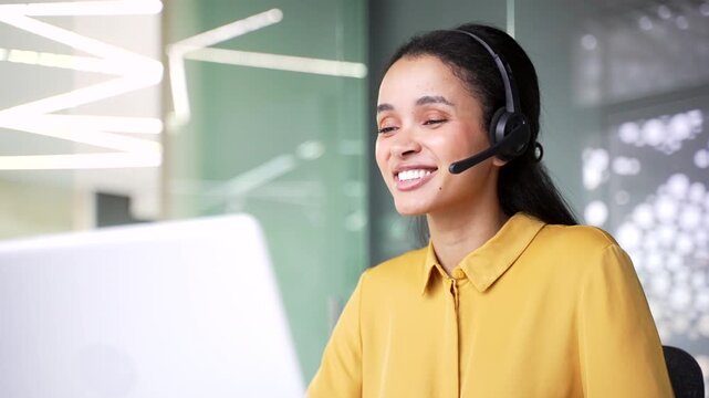 Close up of professional female call center agent wearing headset and talking on video call using laptop. Confident young businesswoman working as operator and providing customer service at office.