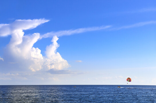 Picturesque view of sea and tourists on a parachute. Topic of summer vacation, travel, leisure and adventure for tourist. Parasailing in the sea. A popular tourist pastime with a parascending