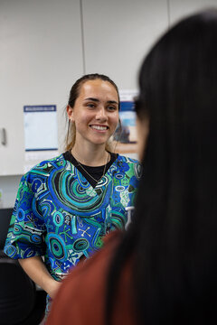 Healthcare worker in patterned scrubs speaking in clinic office