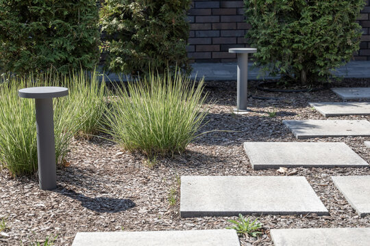 Rectangular concrete stepping stones forming pathway in modern gravel garden with ornamental grass. Real Photo