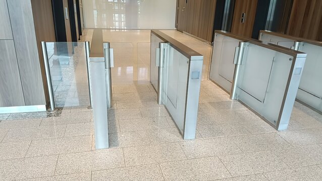 Modern glass turnstiles in corporate office building lobby. Security entrance gate system, access control, interior of business center.