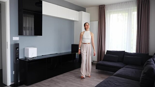Young woman walking through modern apartment and inspecting interior before purchase. Female independence and successful property ownership concept