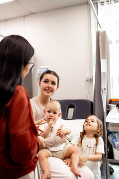 Woman talking to a young mother with two children inside a healthcare facility