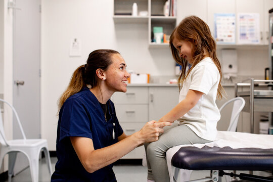 Female nurse happily interacting with child in medical office