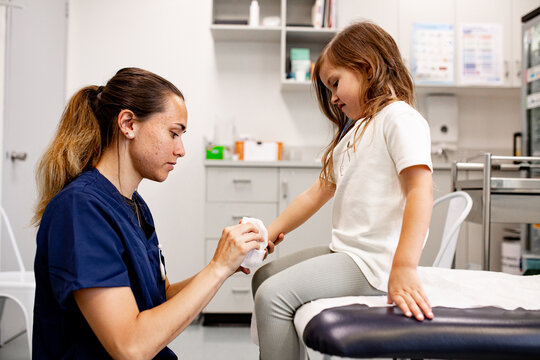 Female healthcare professional carefully bandaging a child&rsquo;s hand in a clinic
