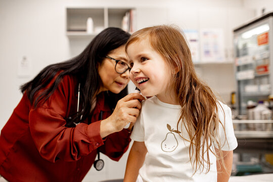 An ENT doctor examining a child&rsquo;s ear with an otoscope in a clinic