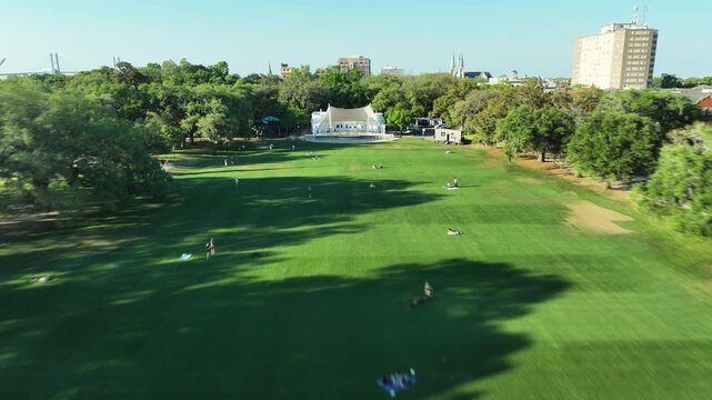 Drone hyper-lapse of Forsyth Park in Savannah, Georgia, capturing its iconic fountain, sprawling green lawns, oak-lined paths, and the charming historic district beyond.