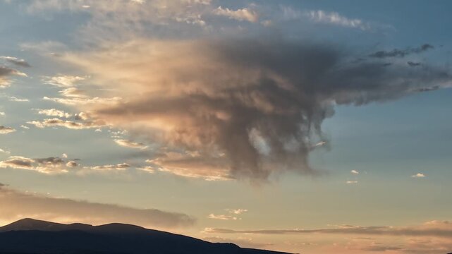 4K static timelapse captures a striking, solitary raincloud dropping an isolated rain shaft. Cinematic meteorological footage reveals shifting sunset colors illuminating the desert sky.