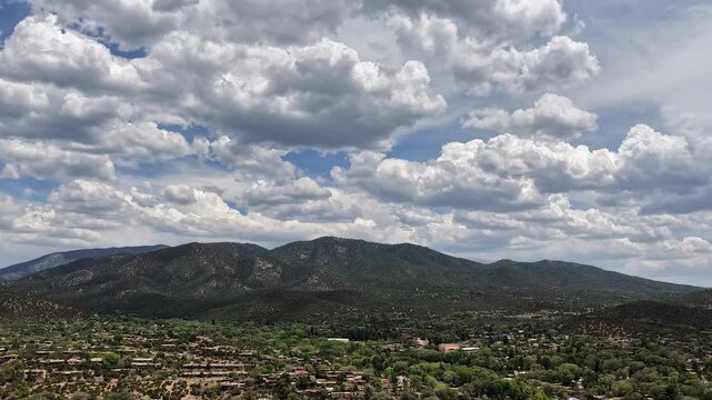 4K static timelapse captures majestic, dramatic cloud layers moving over the rugged landscape of northern Santa Fe, New Mexico. Cinematic meteorological footage reveals shifting moody weather.