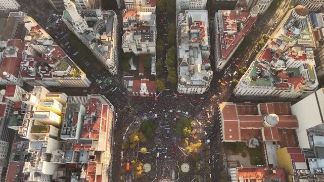 Aerial overhead view of thousands gathered in Argentina for a student strike at sunset. This 4K drone footage reveals the historic Plaza de Mayo filled with demonstrators supporting public education