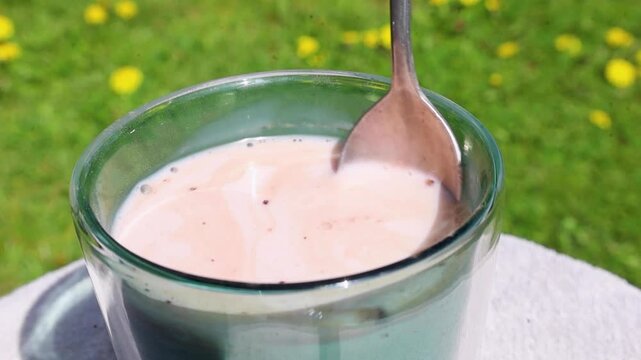Video stirring a glass of milk mixing it with cocoa powder.