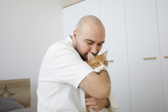 Portrait of man holding fluffy cat pet and having fun together at home