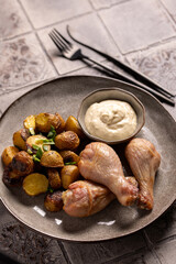 Fototapeta premium Fried Chicken Drumsticks with Baked Potatoes and Sauce on a Ceramic Plate