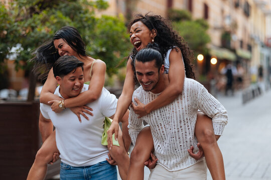 Diverse friends enjoying piggyback ride in urban street