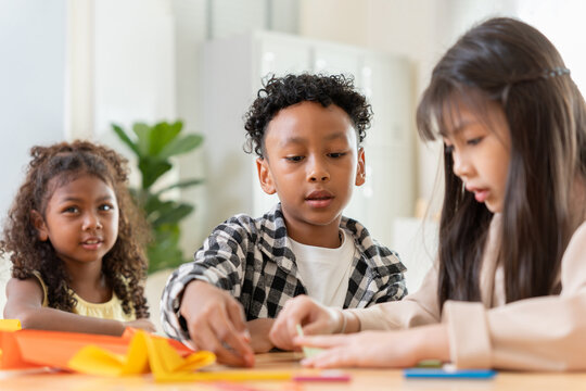 Diverse group of children making origami in classroom, Creative kids having fun with paper craft project together, Happy multi-ethnic students working on creative art project