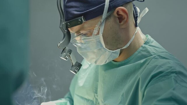 Focused doctor man male surgeon in uniform using electrocautery instrument tool medical equipment cutting burning with smoke doing neurosurgical operation physician practitioner surgery medicine work