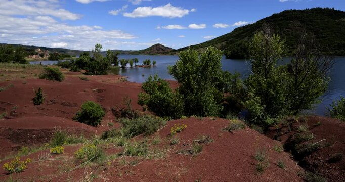 Red landscape surrounding te artificial lake of Salagou, Occitania, Southern France.