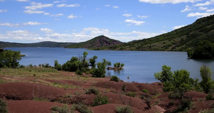 Red landscape surrounding te artificial lake of Salagou, Occitania, Southern France.