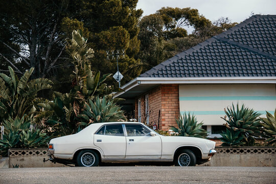 old vintage car parked in front of a brick house