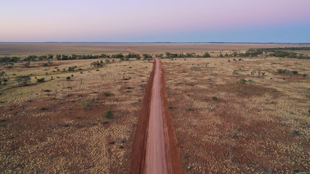 Drone shot of a dirt road going through creek and plain