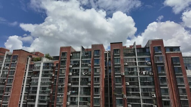 Timelapse of fast moving dramatic clouds over high-density residential apartment complex featuring numerous external air conditioning units and private balconies in Ningbo, China