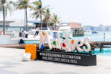 02.05.25, Male, Maldives - sign for "Maldives" sits on a black platform, showcasing WORLDS LEADING DESTINATION, alongside a white boat and palm trees, tropical paradise. , Holiday escape © FOTO_STOCKER