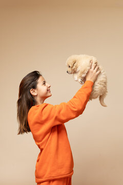 Girl lifting fluffy puppy high and looking with love into its eyes
