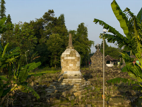 Aerial view of Plaosan Kidul Temple with its ancient stone stupas surrounded by lush green banana trees and tropical vegetation in Kecamatan Prambanan, Jawa Tengah, Indonesia.