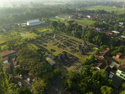 Aerial view of Plaosan Kidul Temple complex with ancient stone ruins and stupas surrounded by lush tropical trees and rural houses Kecamatan Prambanan, Jawa Tengah, Indonesia.