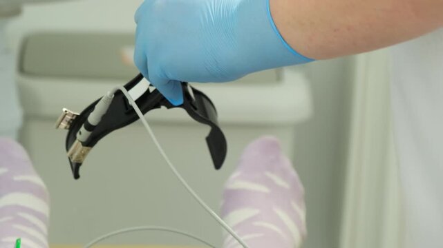 Medical worker sprays electrode clamp before diagnostic test on woman. Specialist cleans device surface preparing clip for accurate signal contact
