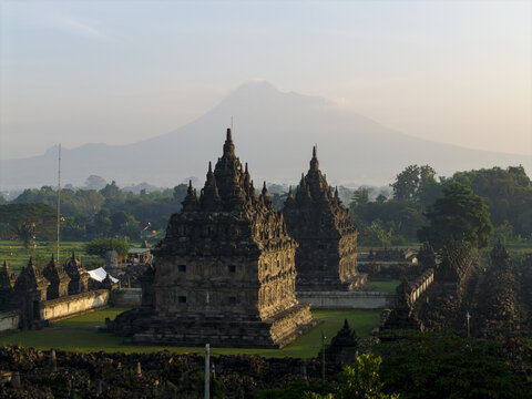 Aerial view of the ancient stone structures of Plaosan Lor Temple with Mount Merapi in the background under soft morning light Kecamatan Prambanan, Jawa Tengah, Indonesia.