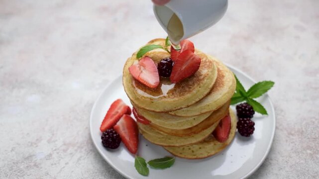 Pouring maple syrup on a delicious pancakes stack