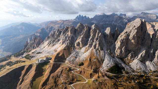 Aerial view of the jagged peaks of Gardena Pass with winding roads and autumn colors in the Dolomites Corvara, Trentino-Alto Adige, Italy.