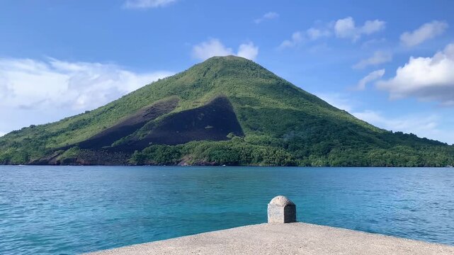 "Scenic View of Banda Api Volcano Island with Tropical Green Mountain, Lava Flow Scars, and Calm Blue Sea in Maluku, Indonesia"