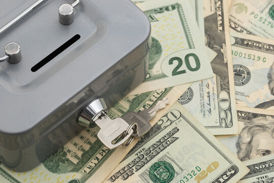 Silver lock box with a key on American money for financial security and savings