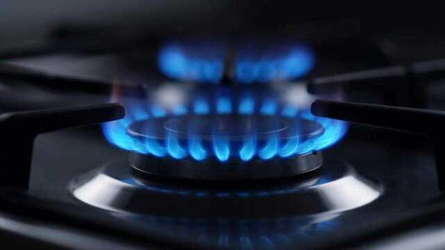 Close up of blue gas flame on a kitchen stove burner.