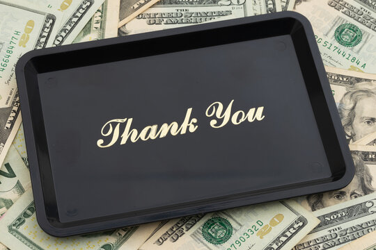 Thank You text on a tip serving tray on twenty dollar bills for tipping culture