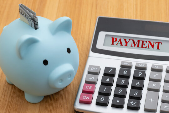 Payment message with blue piggy bank with money and calculator on wood desk