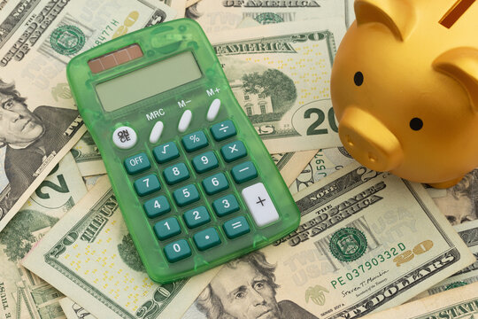 Calculator and piggy bank on twenty dollar bills for budgeting