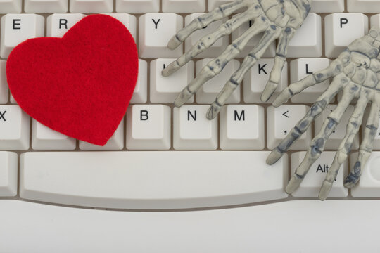 Blank red heart with a skeleton hand white computer keyboard for online romance scams