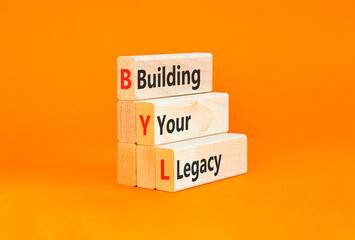 BYL building your legacy symbol. Concept words BYL building your legacy on beautiful wooden blocks. Beautiful orange background. Business BYL building your legacy concept. Copy space. © Dzmitry