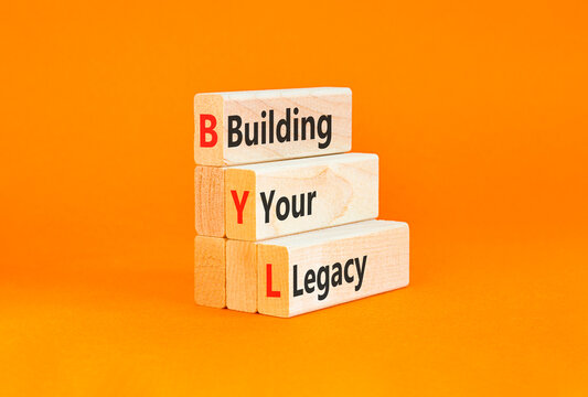 BYL building your legacy symbol. Concept words BYL building your legacy on beautiful wooden blocks. Beautiful orange background. Business BYL building your legacy concept. Copy space.