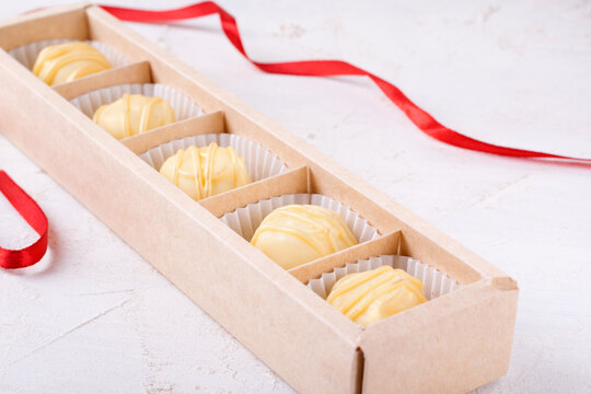 Cheese sweets with white chocolate glazing in the gift box on the white table