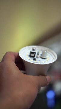 Close-up of an uncovered LED lamp held by hand for repair and electronic component purposes.	