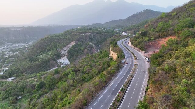 Drone shot of mountain road and Trikuta hills. In the background, the majestic, hazy peaks of the Trikuta Hills&mdash;home to the holy Mata Vaishno Devi shrine.