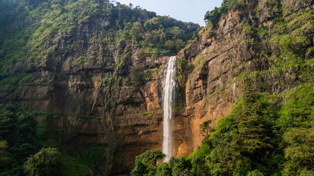 Aerial view of Cikanteh Waterfall cascading down a steep rocky cliff surrounded by lush tropical forest Sukabumi, West Java, Indonesia.