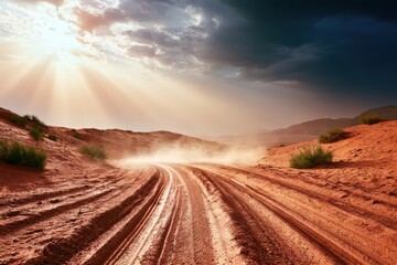 Naklejka premium Dusty dirt road winding through vast red sand desert under dramatic sunset sun rays