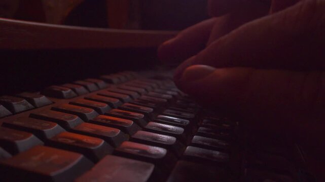  Macro shot of programmer hands coding on laptop keyboard in dark room, slow motion.