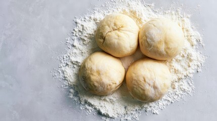 Fototapeta premium Four round balls of fresh raw dough resting on dusting of white wheat flour on textured stone surface